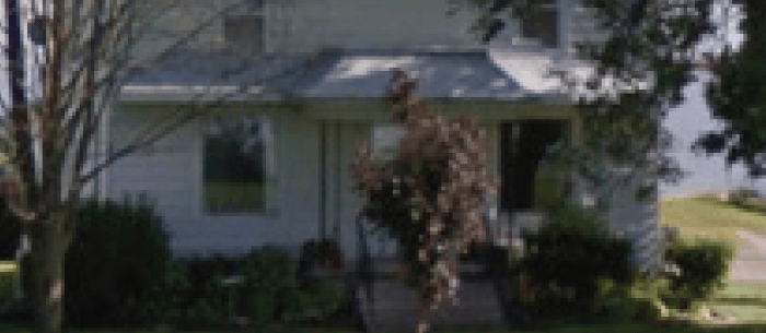 a blurry white house with trees at the front