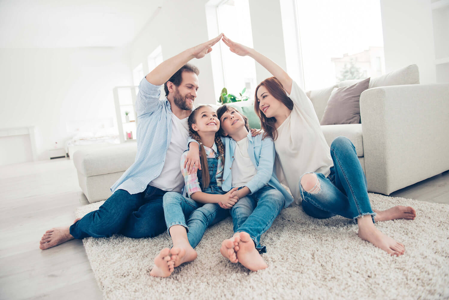 A family sitting on the floor, forming a heart shape with their hands