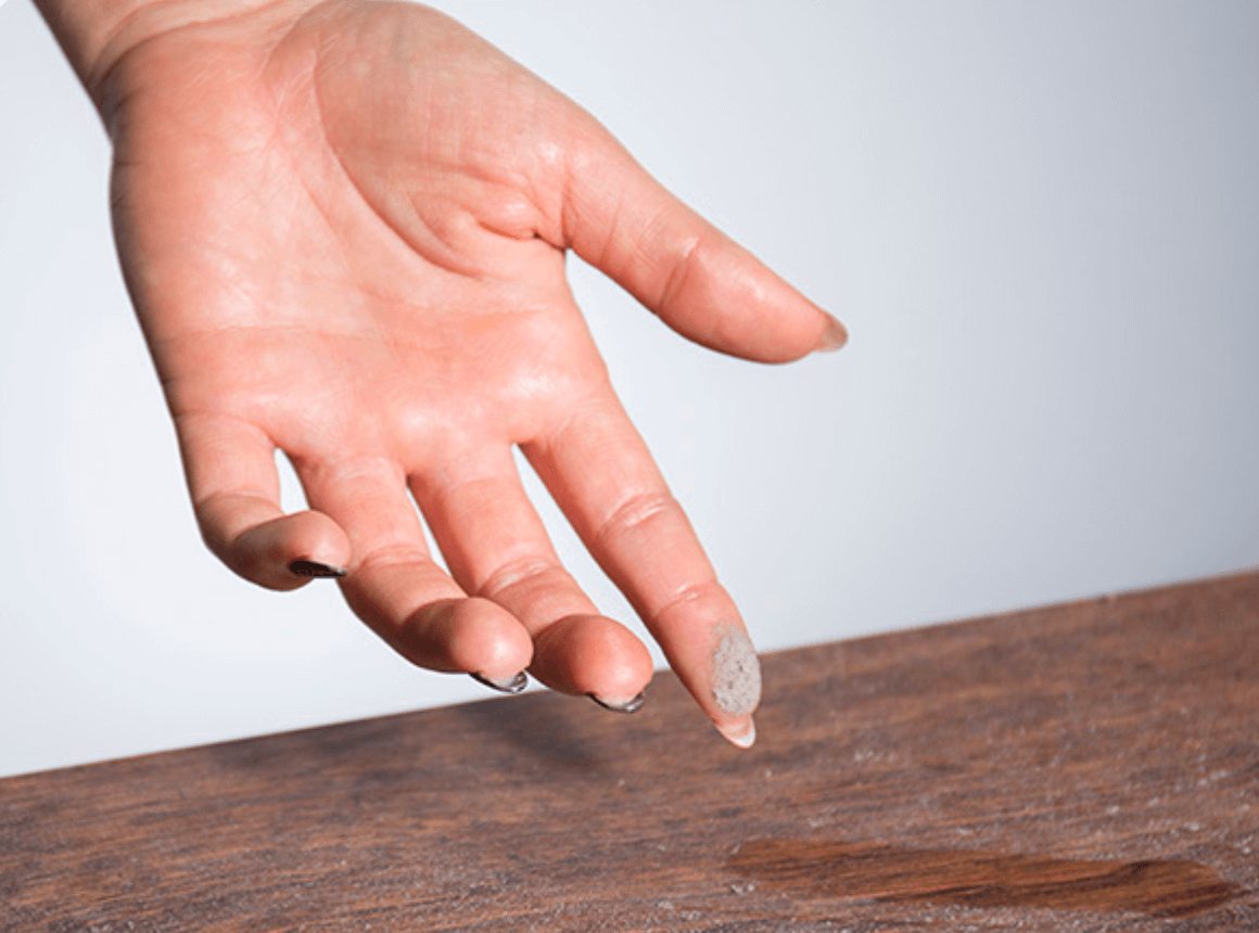 A hand gently touching a smooth wooden surface.
