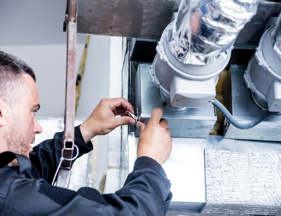 A man fixing a heating unit in a dimly lit room