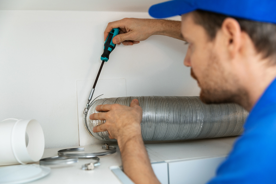 A man in a blue shirt repairing a duct