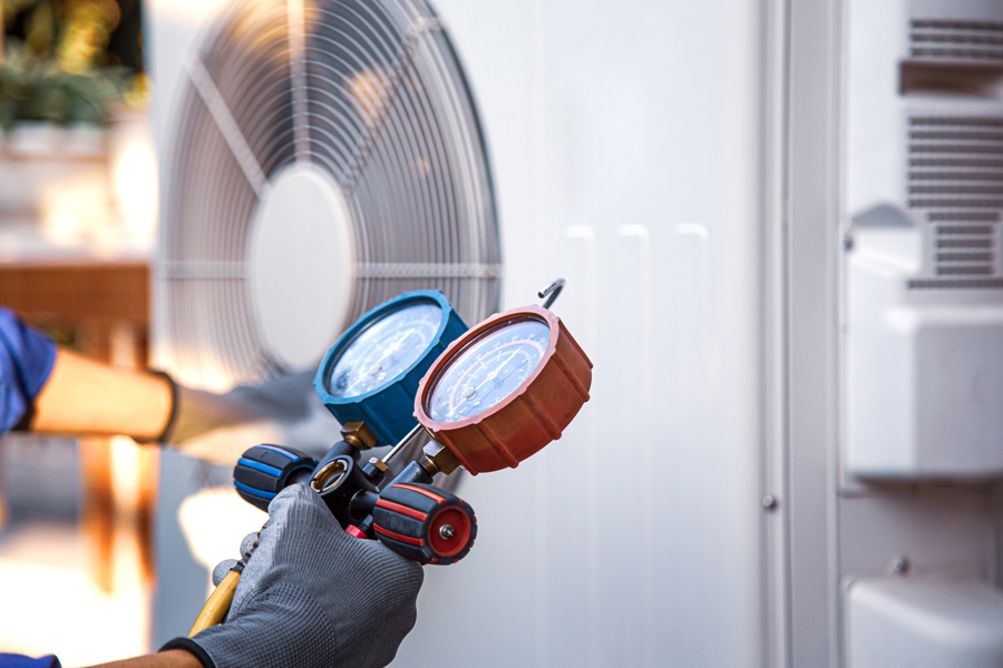 A person wearing blue gloves holding a hose and air conditioner