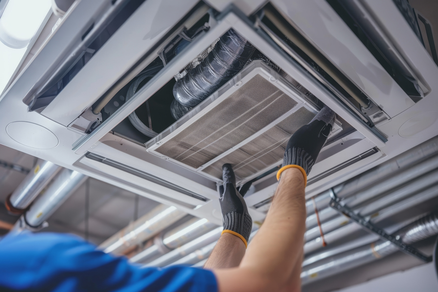 A technician in work attire is fixing an air conditioner