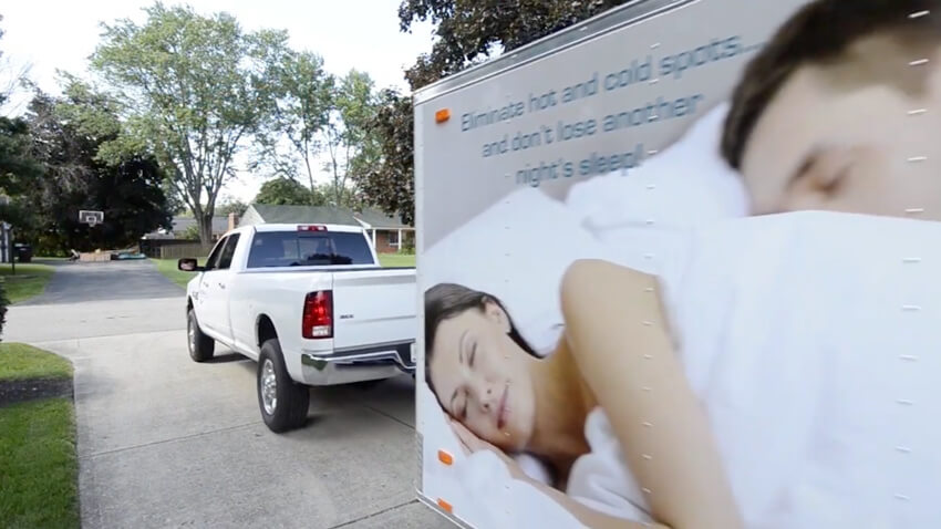 Image of a truck showcasing a big advertisement, with a woman in the background.