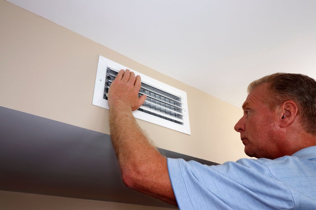 A technician repairs an air conditioner indoors, ensuring optimal HVAC performance for winterizing air ducts.