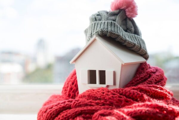 A small house adorned with a hat and scarf, creating a whimsical winter scene