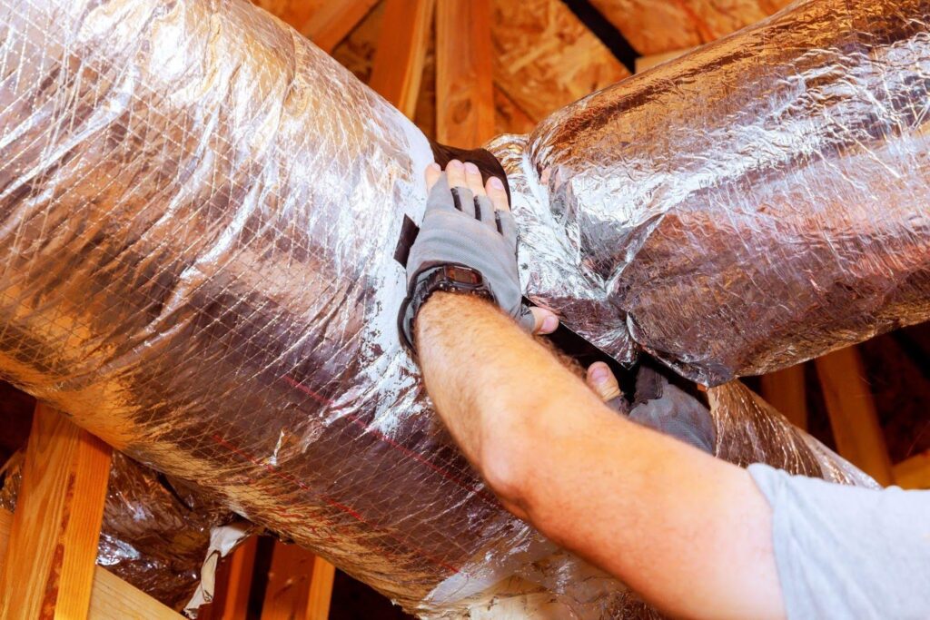 A man fits ductwork securely in a house for optimal heating and cooling