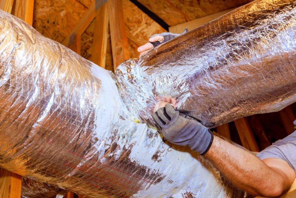 A man is working on a duct installation in a house ensuring proper airflow and ventilation